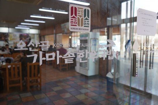 출입문 유리에 적힌 ‘오산골 가마솥한우국밥 KOREAN RESTAURANT’, 안쪽에 홀